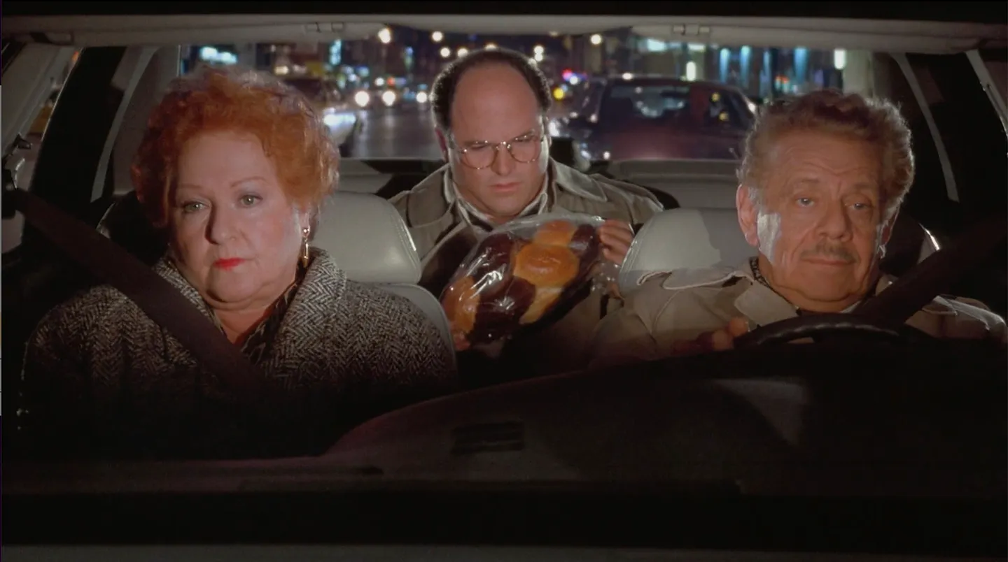 George and his parents in a car, holding a marble rye.