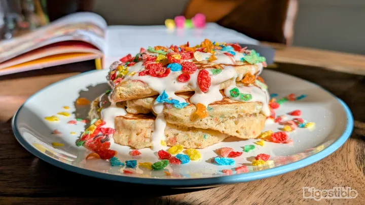 A plate with three pancakes covered in Fruity Pebbles cereal.