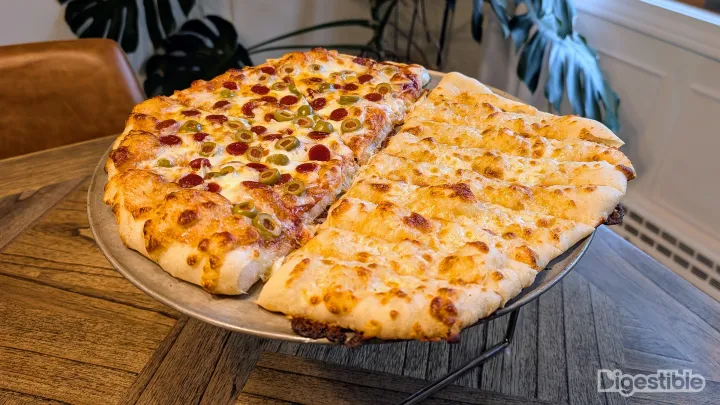 A pizza with breadsticks on one half.